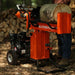 Orange superhandy gas log splitter 25 ton with a log on top, set against a forest background.