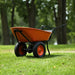 An orange and black superhandy electric wheelbarrow 24v with a visible 24V 7Ah AGM battery.  Front side view outdoors.