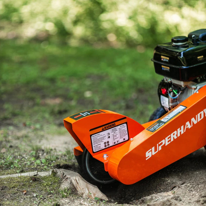 An orange and black SuperHandy stump grinder with a 9HP engine and a 12-inch cutting blade. Side view outdoors in use.