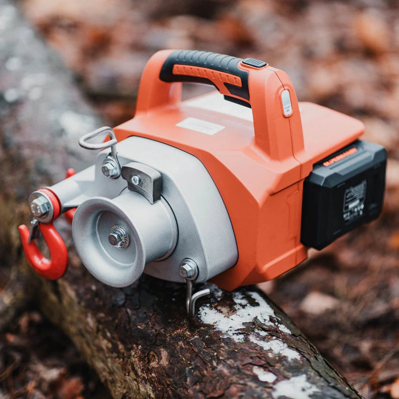 An orange and silver SuperHandy winch with low-stretch rope, featuring two red hooks and a carrying handle. Winch  view outdoors.
