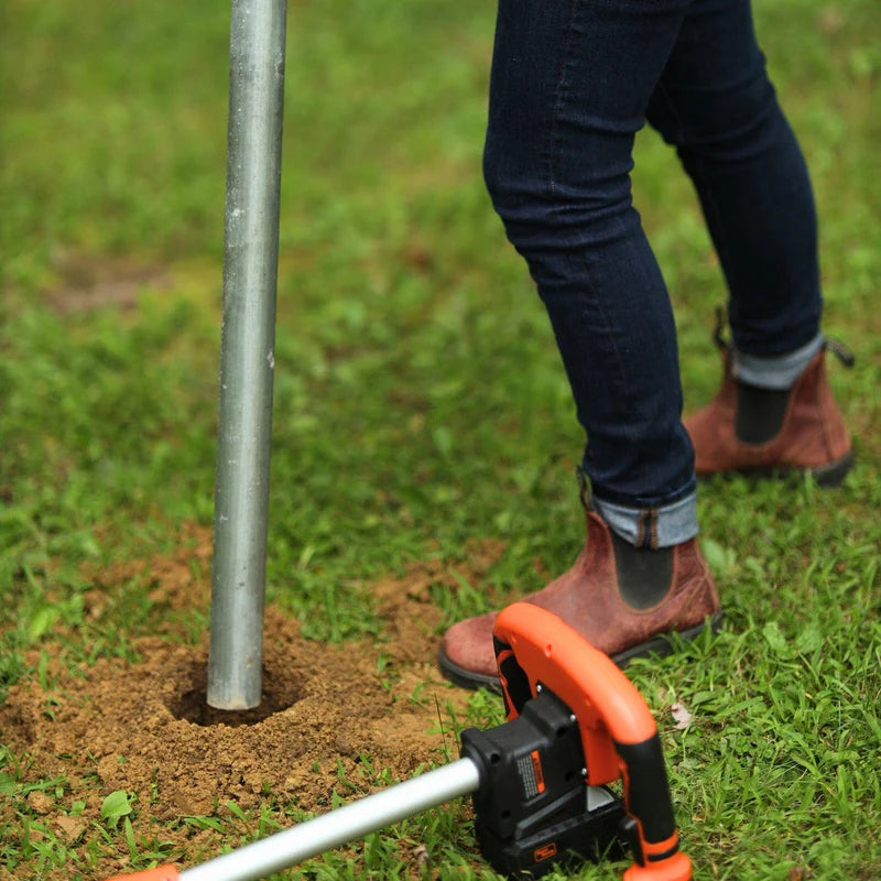 Electric Earth Auger with a 20V 4Ah battery, featuring an orange and black color scheme, with a auger bit inserted vertically. Top view outdoors in use.