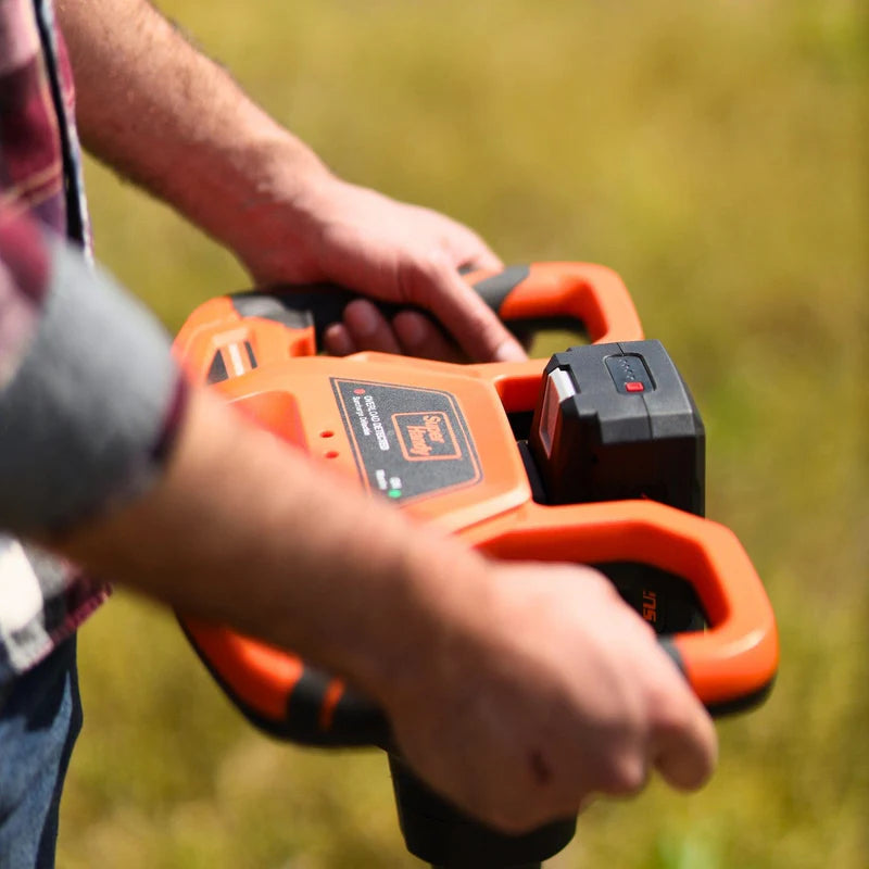 An electric earth auger with a 48V 2Ah battery, featuring an orange and black color scheme and a spiral digging bit. Handle view outdoors in use.