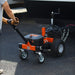 An orange and black electric trailer dolly with four wheels and a control panel. Back view outdoors in use.