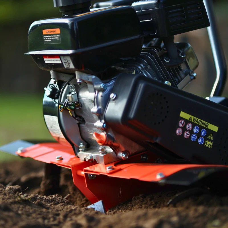 A orange and black gas-powered garden tiller with orange wheels and a 209CC engine. Side view outdoors in use.