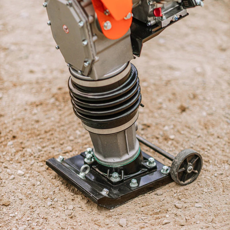 An orange and black SuperHandy  jumping jack tamping rammer with a 7HP 209CC engine, predominantly black and orange in color, designed for soil compaction. Wheel view outdoors.
