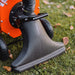 An orange and black gas powered leaf vacuum and wood chipper with a black collection bag and wheels for mobility. Wheel view outdoors in use.
