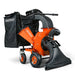 An orange and black gas powered leaf vacuum and wood chipper with a black collection bag and wheels for mobility. Front side view.