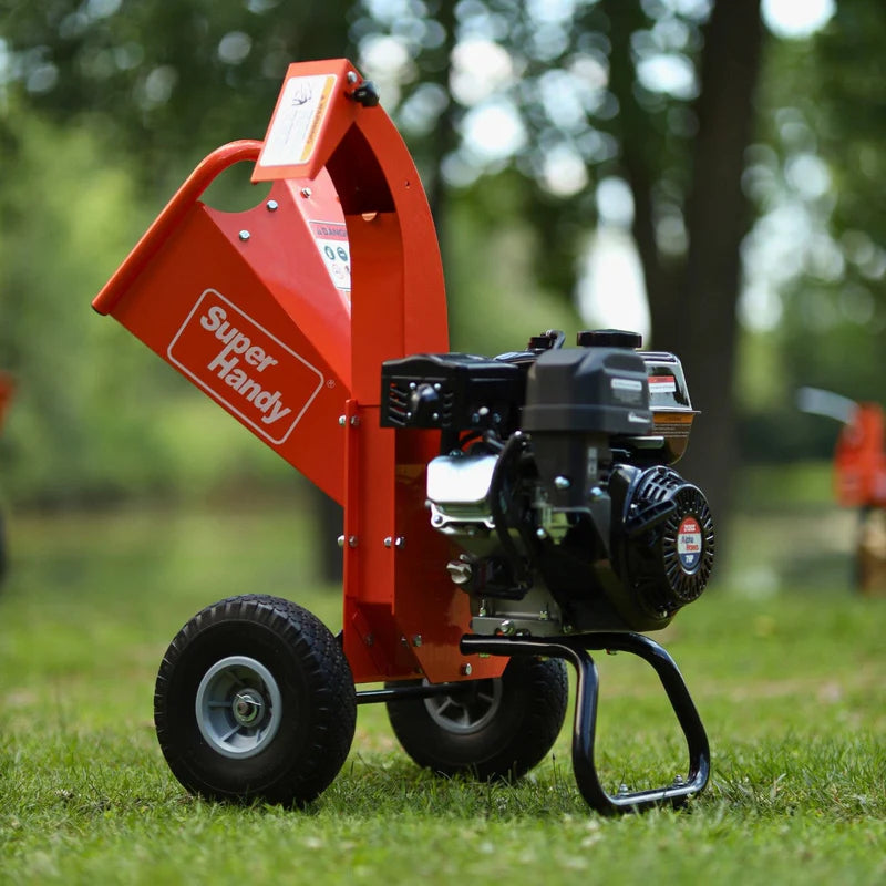 An orange mini wood chipper with a 7HP gas powered engine, equipped with wheels for mobility. Engine view outdoors.