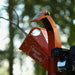 An orange mini wood chipper with a 7HP gas powered engine, equipped with wheels for mobility. Discharge chute view with logo showing.