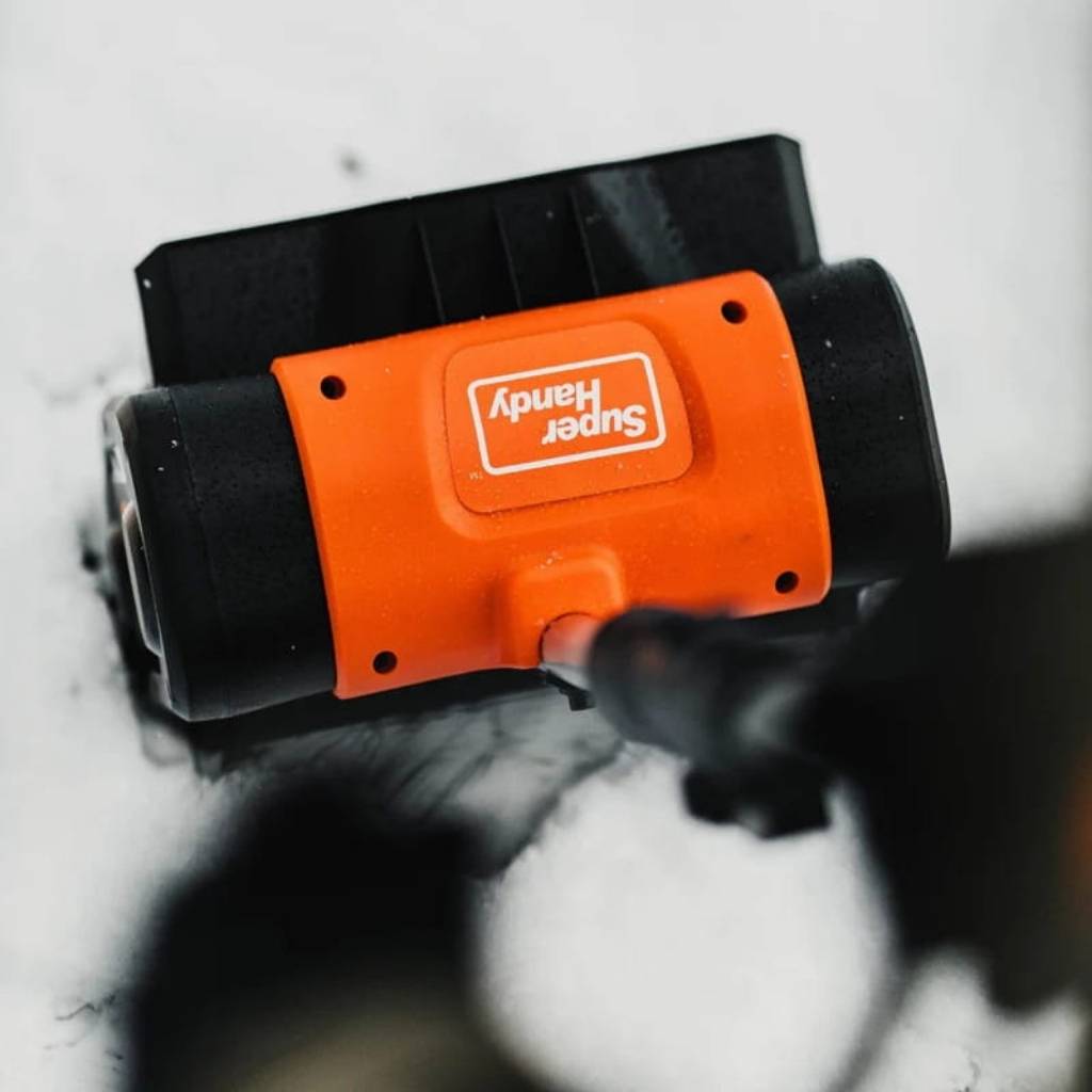 Orange and black superhandy 20 v 2 ah snow blower on a snowy surface with 'Super Handy' branding.