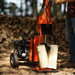 Orange superhandy gas log spliter 25 ton in use with a blurred background of stacked logs.