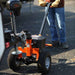 Person using a small orange superhandy 2800 lbs power dolly on a road