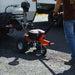 Person using a small orange superhandy 2800 electric dolly on a paved surface with a vehicle in the background.