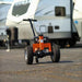 Small orange and black superhandy 2800 lbs electric power dolly on a road with blurred vehicles in the background