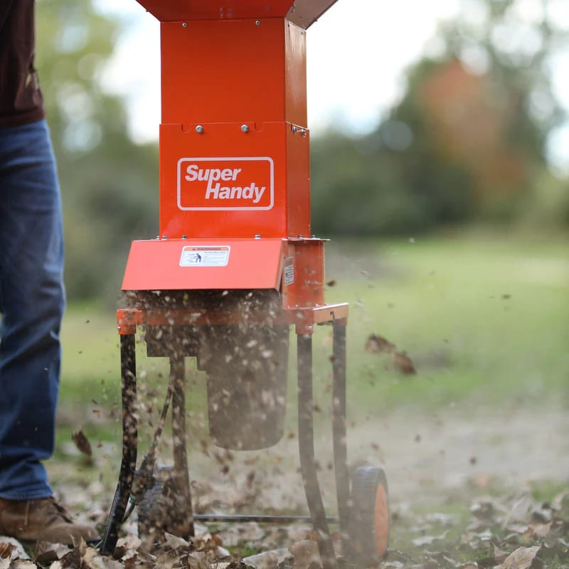 Orange Super Handy electric leaf mulcher shredder in use outdoors with a blurred background