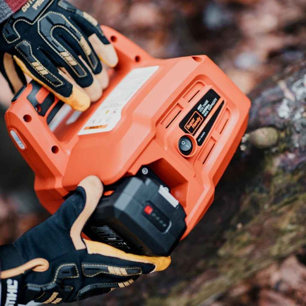 Person wearing gloves holding an orange superhandy electric capstan winch with a blurred natural background