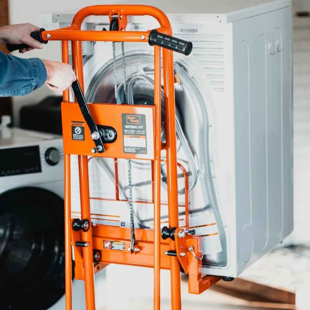 Orange superhandy material lift pallet jack, leaning against a dryer in a laundry room.