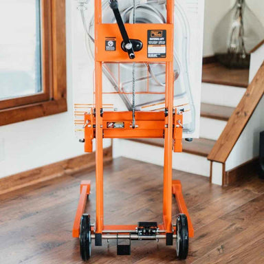 Orange superhandy material lift stacker on a wooden floor with a staircase in the background