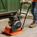 Person operating a super handy vibratory 7 hp plate compactor on a driveway