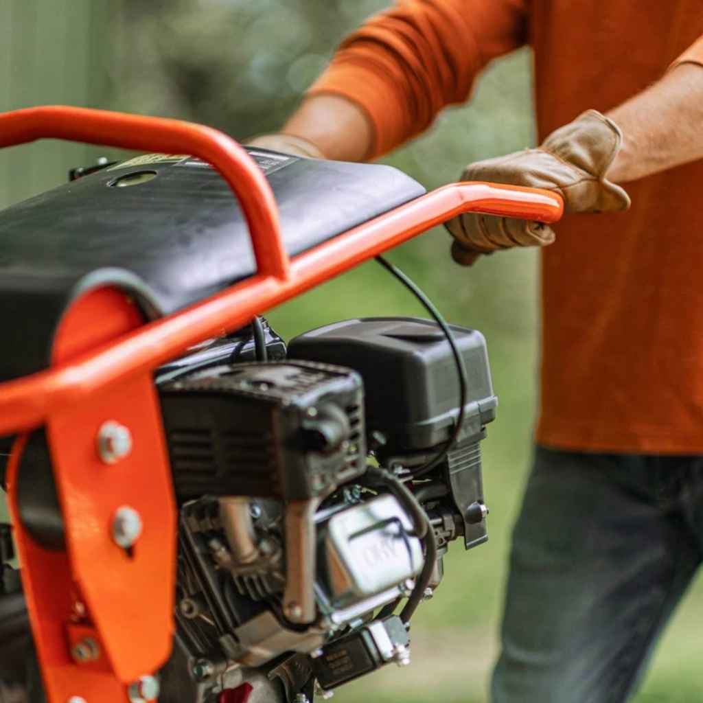 Person holding a red and black superhandy jumping jack tamping rammer with a blurred green background