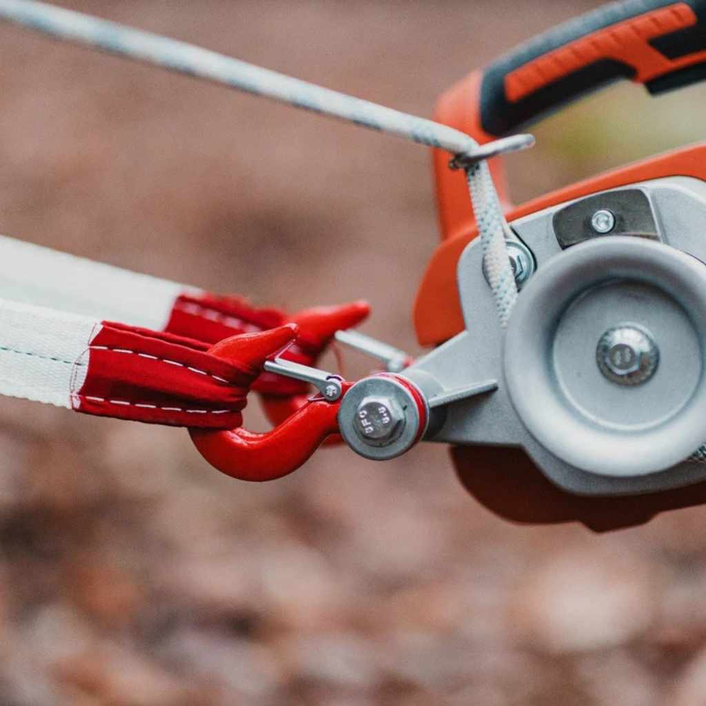 Close-up of a red and gray superhandy electric portable winch with rope against a blurred background